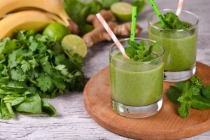 Celery detox drink Fresh organic detox green drink smoothie with celery, spinach, banana, cilantro, lime and ginger with refreshing mint. Healthy, dietary, vegetarian food