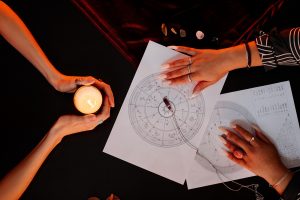Numerology Reading at Seance Top view of female fortune teller reading astrology chart for young woman visiting at spiritual seance